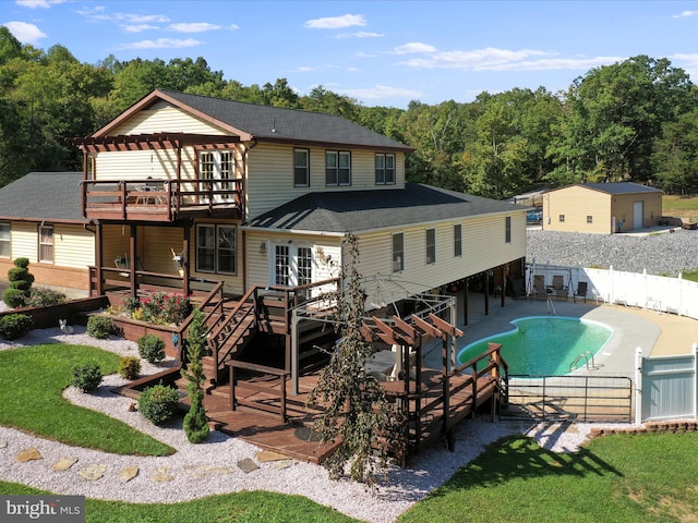 rear view of property with a balcony, a patio, and a swimming pool side deck