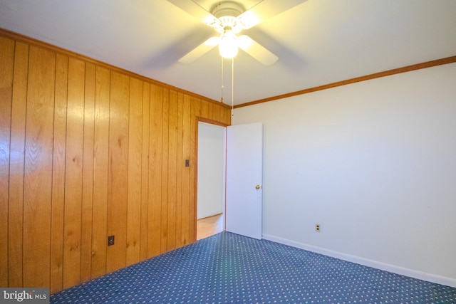 unfurnished bedroom with dark carpet, a closet, wood walls, crown molding, and ceiling fan