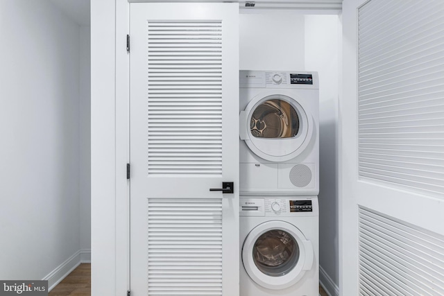 clothes washing area with dark wood-type flooring and stacked washing maching and dryer