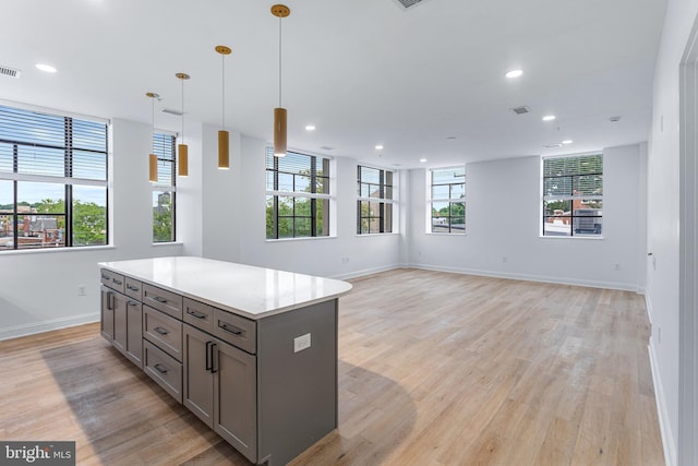 kitchen featuring plenty of natural light, a kitchen island, hanging light fixtures, and light wood-type flooring