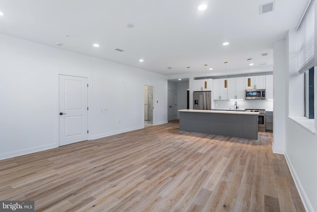 kitchen featuring white cabinets, a kitchen island, light hardwood / wood-style flooring, stainless steel appliances, and decorative light fixtures