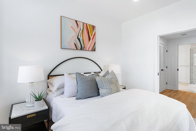 bedroom with light hardwood / wood-style flooring and connected bathroom