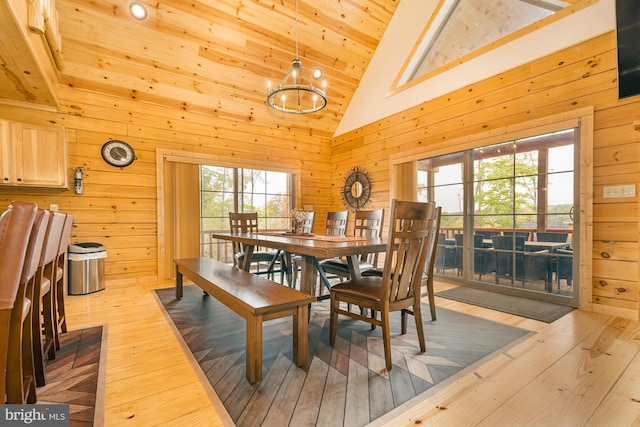 dining space with high vaulted ceiling, wood walls, light wood-type flooring, wooden ceiling, and a notable chandelier