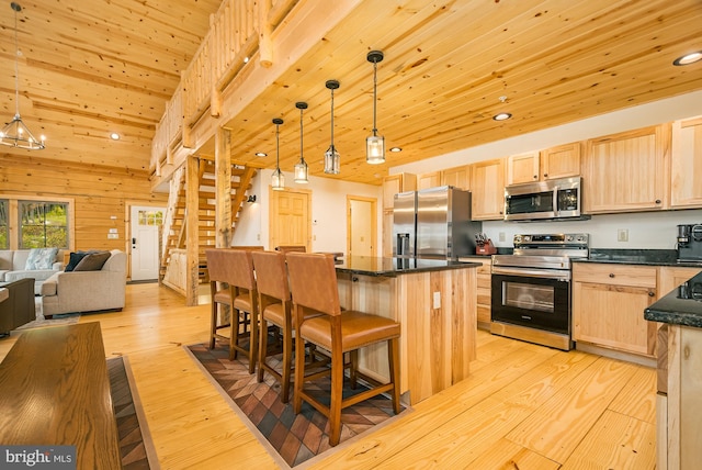 kitchen featuring pendant lighting, appliances with stainless steel finishes, light wood-type flooring, and light brown cabinets