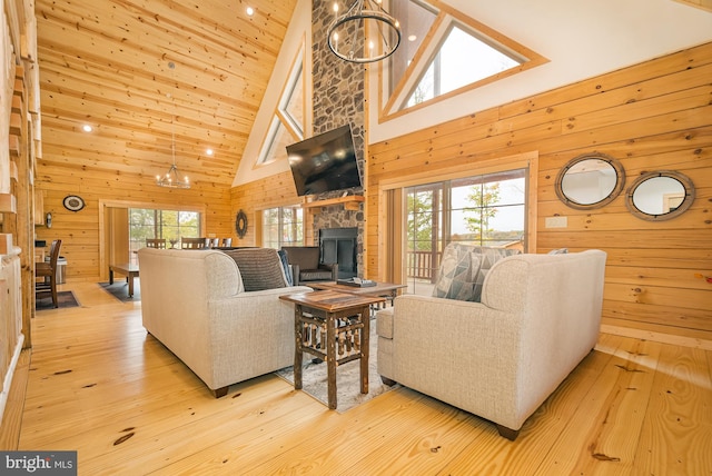 living room with light hardwood / wood-style flooring, an inviting chandelier, wooden walls, and a healthy amount of sunlight