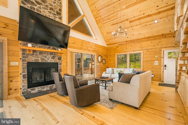 living room featuring a stone fireplace, wooden walls, light wood-type flooring, and high vaulted ceiling