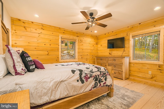 bedroom featuring wooden walls, light hardwood / wood-style floors, and ceiling fan