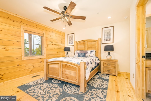 bedroom featuring wood walls, light hardwood / wood-style floors, and ceiling fan