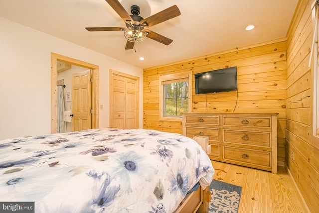 bedroom with wooden walls, ceiling fan, and light hardwood / wood-style flooring