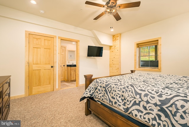 bedroom featuring light carpet, ensuite bath, sink, and ceiling fan