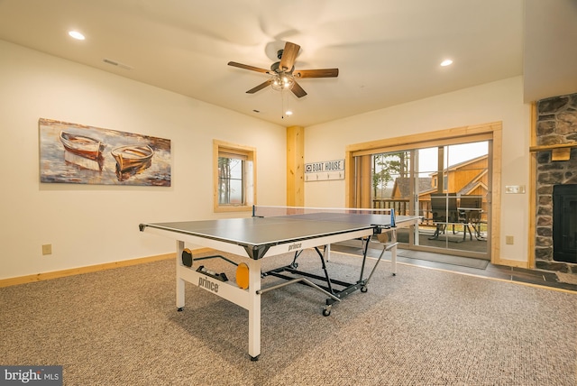 playroom featuring ceiling fan, plenty of natural light, carpet floors, and a stone fireplace