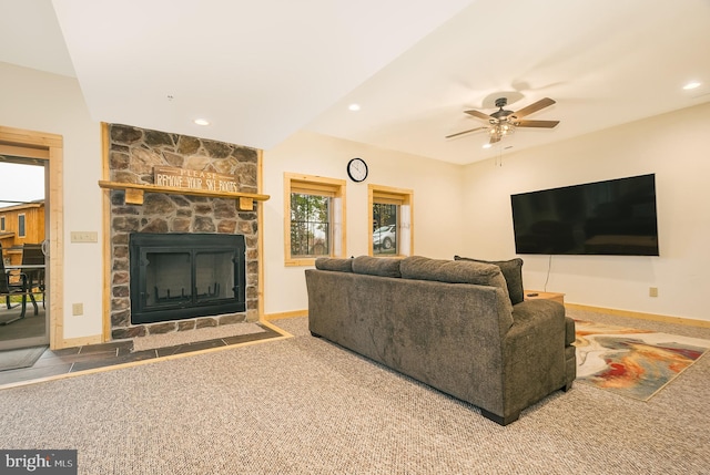 living room with ceiling fan, a stone fireplace, and carpet floors