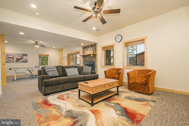 living room with ceiling fan, light colored carpet, and a stone fireplace