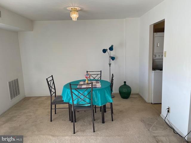 carpeted dining room featuring stacked washer and dryer