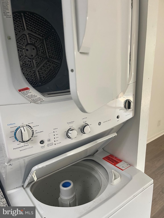 laundry room featuring hardwood / wood-style floors and stacked washer / drying machine