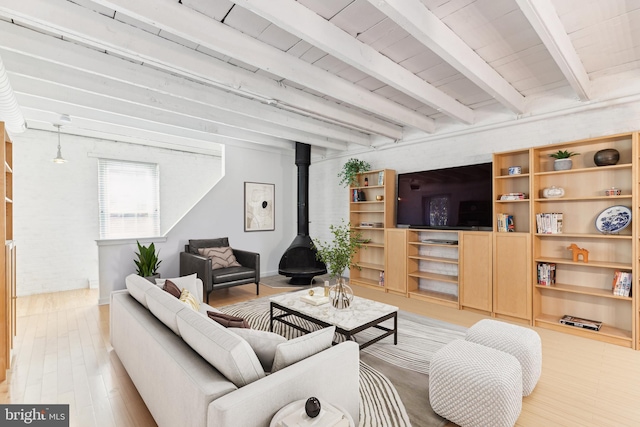 living room featuring light hardwood / wood-style floors, a wood stove, and beam ceiling