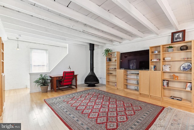 living room featuring beamed ceiling, light hardwood / wood-style flooring, and a wood stove