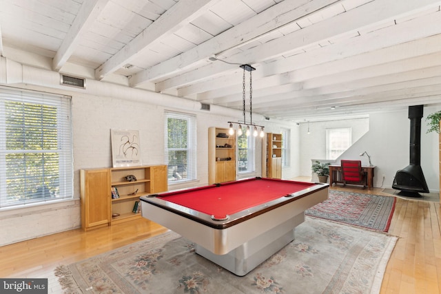 rec room featuring light wood-type flooring, a wood stove, and a wealth of natural light