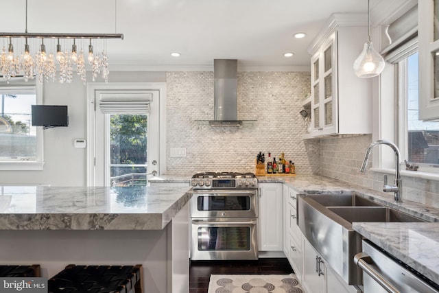 kitchen with appliances with stainless steel finishes, wall chimney exhaust hood, and white cabinetry