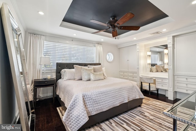 bedroom with built in desk, ceiling fan, a raised ceiling, and hardwood / wood-style floors