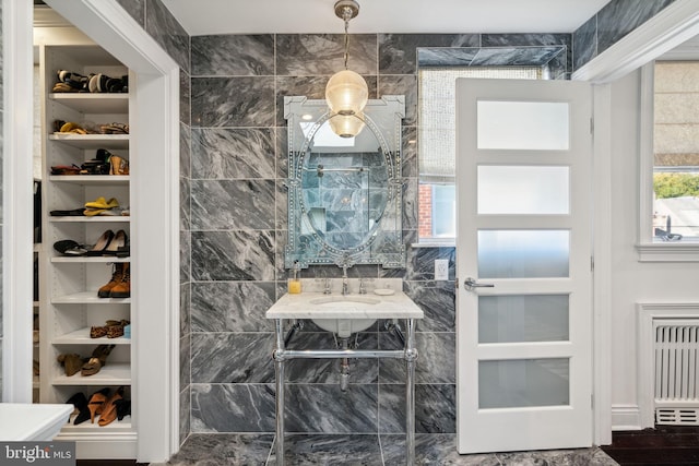 interior space featuring radiator heating unit, sink, and tile walls