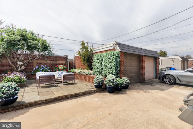 view of patio featuring an outdoor structure, outdoor lounge area, fence, and a garage