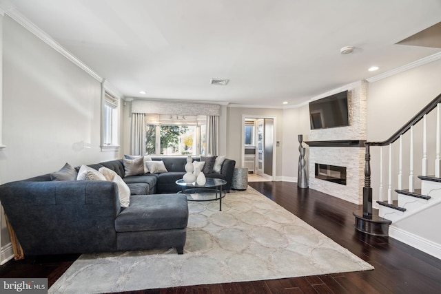 living room with crown molding, a stone fireplace, and wood-type flooring