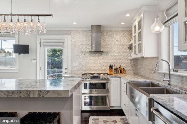 kitchen featuring wall chimney exhaust hood, stainless steel appliances, decorative backsplash, and glass insert cabinets