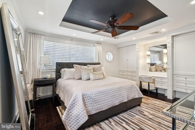 bedroom featuring wood-type flooring, visible vents, a raised ceiling, and crown molding