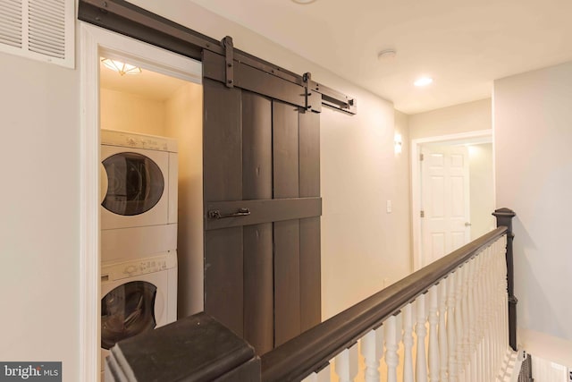 laundry room with a barn door and stacked washing maching and dryer