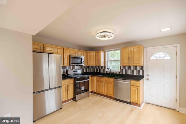 kitchen featuring stainless steel appliances, light hardwood / wood-style floors, tasteful backsplash, and sink