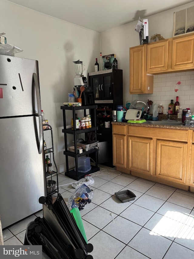 kitchen featuring stainless steel refrigerator, sink, light tile patterned floors, and decorative backsplash