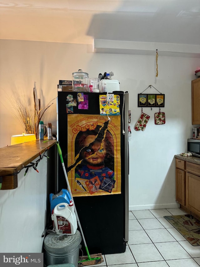 interior space with black fridge and light tile patterned flooring