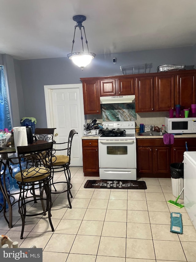 kitchen with pendant lighting, light tile patterned flooring, sink, white appliances, and backsplash