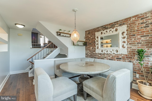 dining area with hardwood / wood-style flooring and brick wall