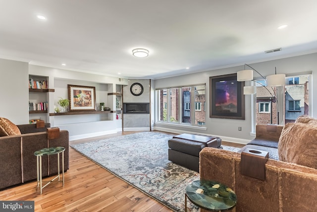 living room featuring crown molding, a fireplace, and wood-type flooring