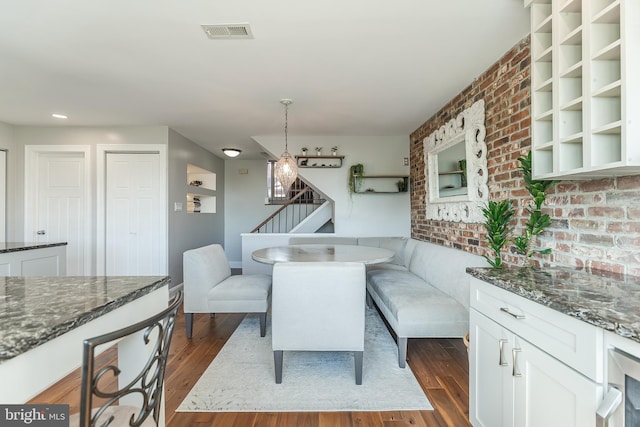 dining area with beverage cooler, brick wall, and dark hardwood / wood-style flooring