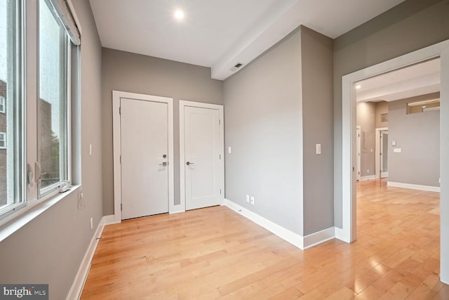 unfurnished bedroom featuring light hardwood / wood-style flooring and multiple closets