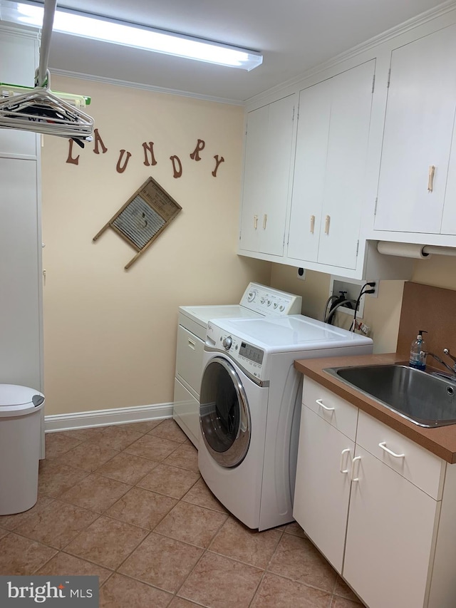 laundry area with light tile patterned floors, cabinets, sink, and washing machine and clothes dryer