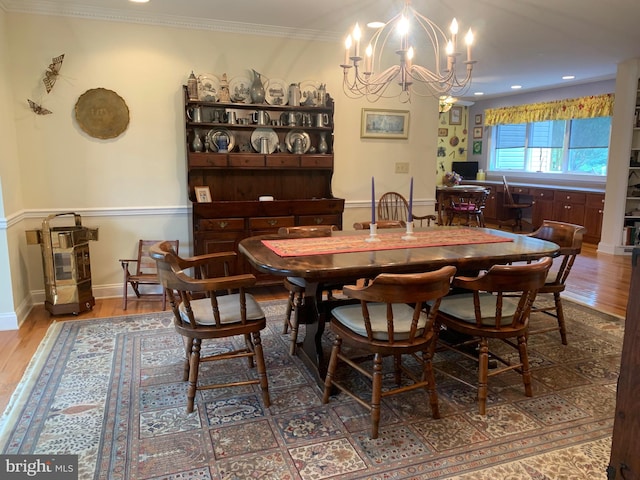 dining area featuring ornamental molding, an inviting chandelier, and hardwood / wood-style floors