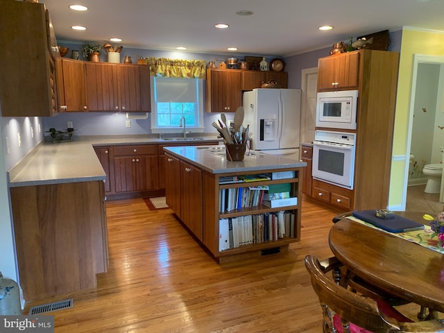 kitchen with a center island, sink, light hardwood / wood-style flooring, white appliances, and ornamental molding