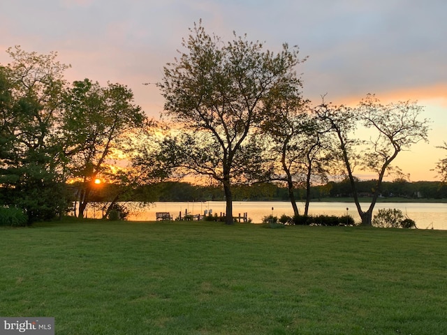 yard at dusk featuring a water view