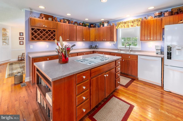 kitchen featuring white appliances, a center island, light hardwood / wood-style flooring, and sink