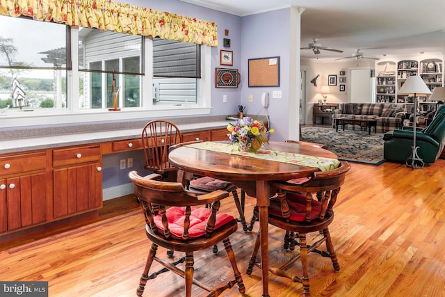 dining room with built in desk, crown molding, light hardwood / wood-style floors, and ceiling fan