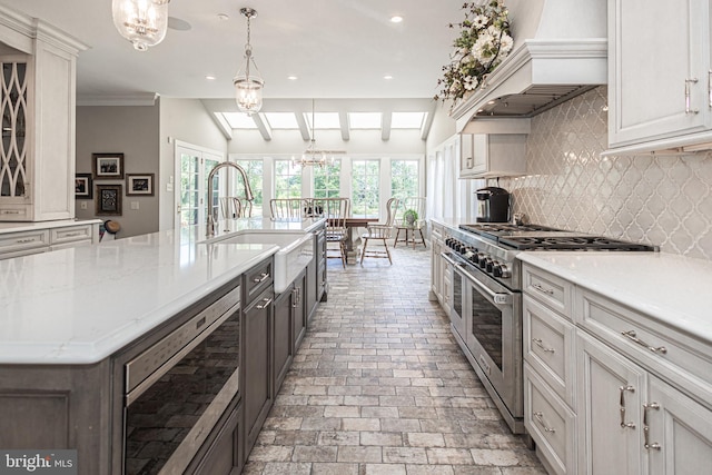 kitchen with double oven range, decorative backsplash, decorative light fixtures, and a wealth of natural light