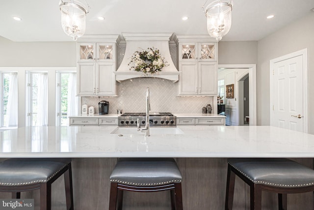 kitchen featuring a kitchen breakfast bar, white cabinets, custom range hood, and a spacious island