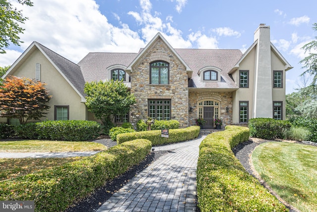 french country inspired facade with a front yard