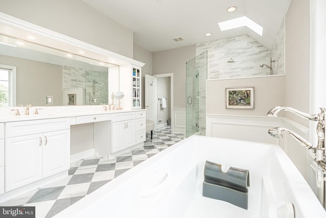 bathroom with a skylight, independent shower and bath, and vanity