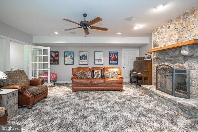 living room featuring ceiling fan, carpet floors, and a stone fireplace