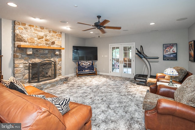 living room with french doors, a stone fireplace, carpet flooring, and ceiling fan